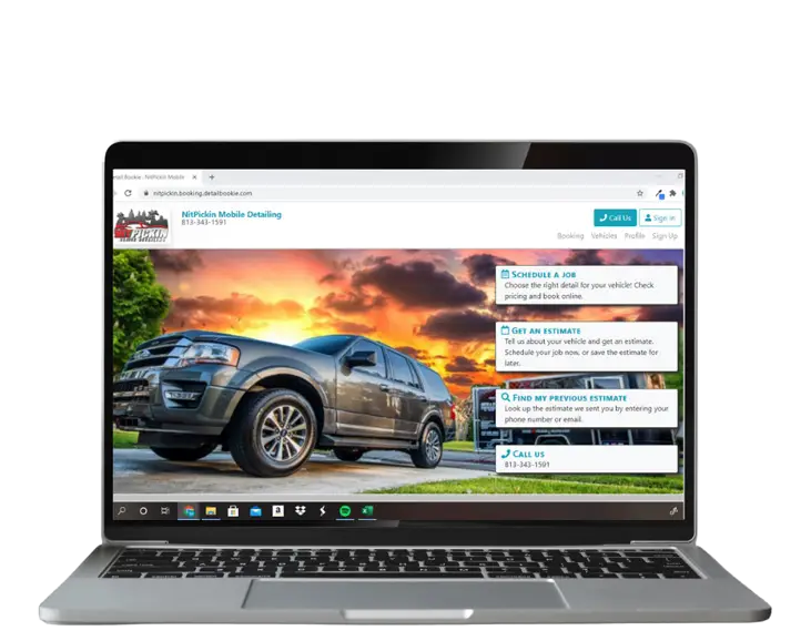 Laptop displaying a car detailing website with a sunset background.
